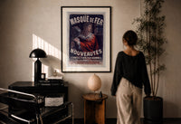 Cheret Au Masque de Fer print in a black frame on a sunlit plaster wall, a woman looking on beside a mushroom lamp