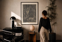 Dore Wood of the Harpies print in a black frame on a sunlit plaster wall, a woman looking on beside a mushroom lamp