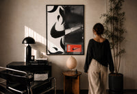 Nike Swoosh Streetwear print in a black frame on a sunlit plaster wall, a person looking on beside a mushroom lamp
