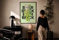 Green Glow Skeleton Bearbrick print in a black frame on a sunlit plaster wall, a person looking on beside a mushroom lamp