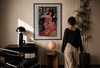 Mucha JOB print in a black frame on a sunlit plaster wall, a woman looking on beside a mushroom lamp