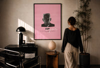 Tyler the Creator IGOR print in a black frame on a sunlit plaster wall, a person looking on beside a mushroom lamp