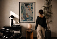 Hokusai Ono Waterfall Kiso Road print in a black frame on a sunlit plaster wall, a woman looking on beside a mushroom lamp