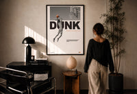 Basketball Dunk Motivation print in a black frame on a sunlit plaster wall, a person looking on beside a mushroom lamp