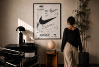 Nike Swoosh Black and White Typography print in a black frame on a sunlit wall with a viewer