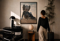 KAWS Companion Desert Monochrome Streetwear print in a black frame on a sunlit wall with a viewer