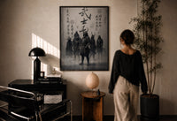 Samurai Bushido Warriors print in a black frame on a sunlit plaster wall, a woman looking on beside a mushroom lamp