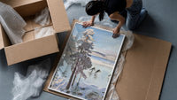 ice skaters on a frozen lake among snowy pines vintage art print framed print being unpacked from protective bubble wrap…