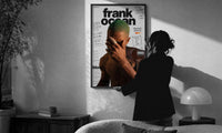 Frank Ocean Blonde Annotated Album Cover print in a slim black frame being hung on a sunlit wall in a monochrome room
