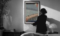 Hiroshige Sudden Shower Ohashi print in a slim black frame being hung on a sunlit wall in a monochrome room