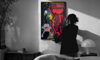 KAWS Down Time Skeleton Companion print in a slim black frame being hung on a sunlit wall in a monochrome room