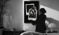 ASAP Rocky At Long Last Rings print in a slim black frame being hung on a sunlit wall in a monochrome room