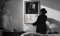 Drake Scorpion Album Tracklist print in a slim black frame being hung on a sunlit wall in a monochrome room