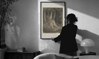 Dore Dante in the Dark Wood print in a slim black frame being hung on a sunlit wall in a monochrome room