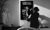Kurt Cobain Nirvana Live print in a slim black frame being hung on a sunlit wall in a monochrome room