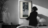 Crepe de Chine Millot Parfum print in a slim black frame being hung on a sunlit wall in a monochrome room