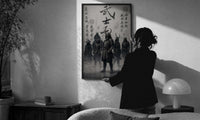 Samurai Bushido Warriors print in a slim black frame being hung on a sunlit wall in a monochrome room
