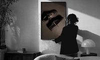 Air Jordan 1 x Travis Scott Velvet Brown Mocha print in a slim black frame being hung on a sunlit wall in a monochrome room