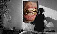 AMG Grillz Gold Grill print in a slim black frame being hung on a sunlit wall in a monochrome room