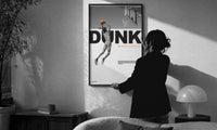 Basketball Dunk Motivation print in a slim black frame being hung on a sunlit wall in a monochrome room