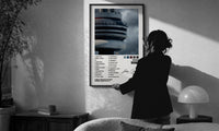 Drake Views CN Tower Tracklist print in a slim black frame being hung on a sunlit wall in a monochrome room