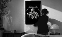 Metallica Decaying Corpse Skeleton print in a slim black frame being hung on a sunlit wall in a monochrome room