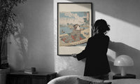 Kuniyoshi Water Scene with Boat print in a slim black frame being hung on a sunlit wall in a monochrome room