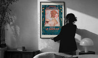 Jabon Hiel de Vaca La Giralda print in a slim black frame being hung on a sunlit wall in a monochrome room