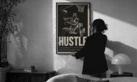 Dennis Rodman Hustle Basketball print in a slim black frame being hung on a sunlit wall in a monochrome room