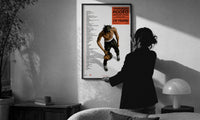 Travis Scott Rodeo Anniversary print in a slim black frame being hung on a sunlit wall in a monochrome room