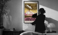 WPA Lassen Volcanic Park print in a slim black frame being hung on a sunlit wall in a monochrome room