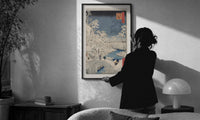 Hiroshige Meguro Bridge in Snow print in a slim black frame being hung on a sunlit wall in a monochrome room
