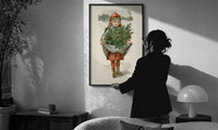 Louis Prang Little Girl with Holly print in a slim black frame being hung on a sunlit wall in a monochrome room