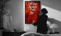 Off the Beaten Path KAWS-Inspired Red Plush print in a slim black frame being hung on a sunlit wall in a monochrome room