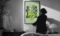 Green Glow Skeleton Bearbrick print in a slim black frame being hung on a sunlit wall in a monochrome room