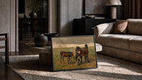 Group of horses in field print in a slim black frame leaning on a travertine coffee table