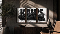 KAWS Monochrome Family Poster Set of 3 in walnut frames above a sideboard in a warm room