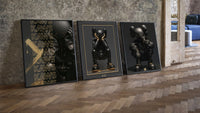 KAWS Noir XX Black Gold Poster Set of 3 leaning on parquet beside a vintage loft door