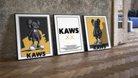 KAWS Monogram Impact Hypebeast Wall Art Set of 3 leaning on parquet beside a vintage loft door