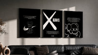 KAWS Monochrome Wall Art Set triptych in three black frames on a grey wall above a leather sofa
