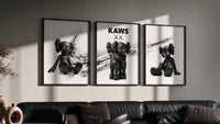 KAWS x Nike Blackout Poster Set of 3 in black frames on a grey wall above a leather sofa