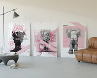 Pink KAWS Companion Triptych displayed beside a brown leather sofa