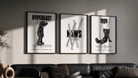 KAWS Black & White Classics triptych in three black frames on a grey wall above a leather sofa