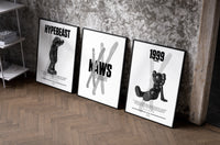 KAWS Black & White Classics set of three black-framed prints leaning against a raw-plaster wall