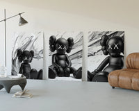 KAWS Est. 1999 Companion three-panel set displayed beside a brown leather sofa