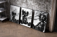 KAWS Est. 1999 Companion set of three black-framed prints leaning against a raw-plaster wall