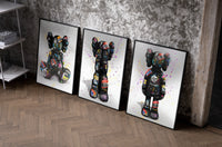 KAWS Companion Graffiti Triptych as black-framed prints leaning against a raw-plaster wall