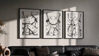KAWS XX Crosshatch Triptych in black frames on a grey wall above a leather sofa