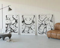 KAWS XX Crosshatch Triptych displayed beside a brown leather sofa
