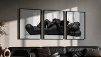 KAWS Reclining Companion Triptych in black frames on a grey wall above a leather sofa